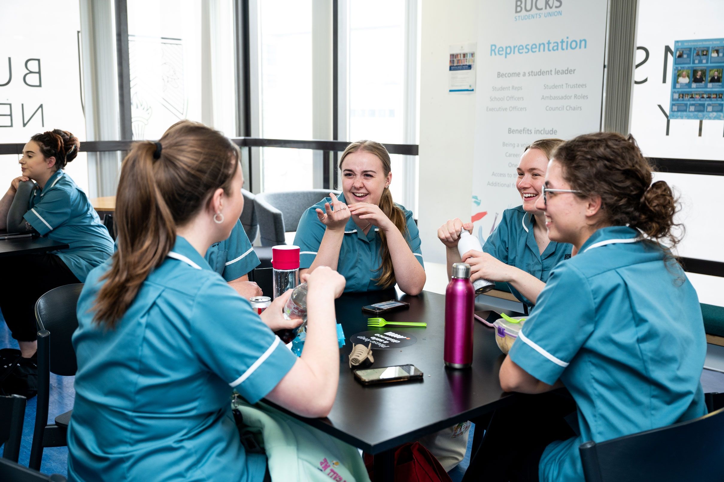 Five nursing students sat around a square table enjoying a break whilst in conversation